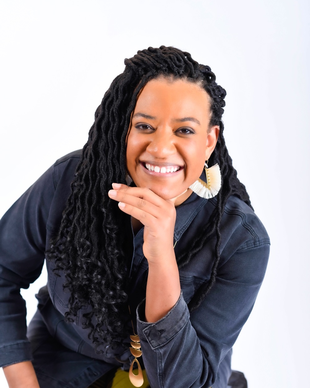 Ebony Johnson leans toward the camera, chin resting on her hand, smiling broadly