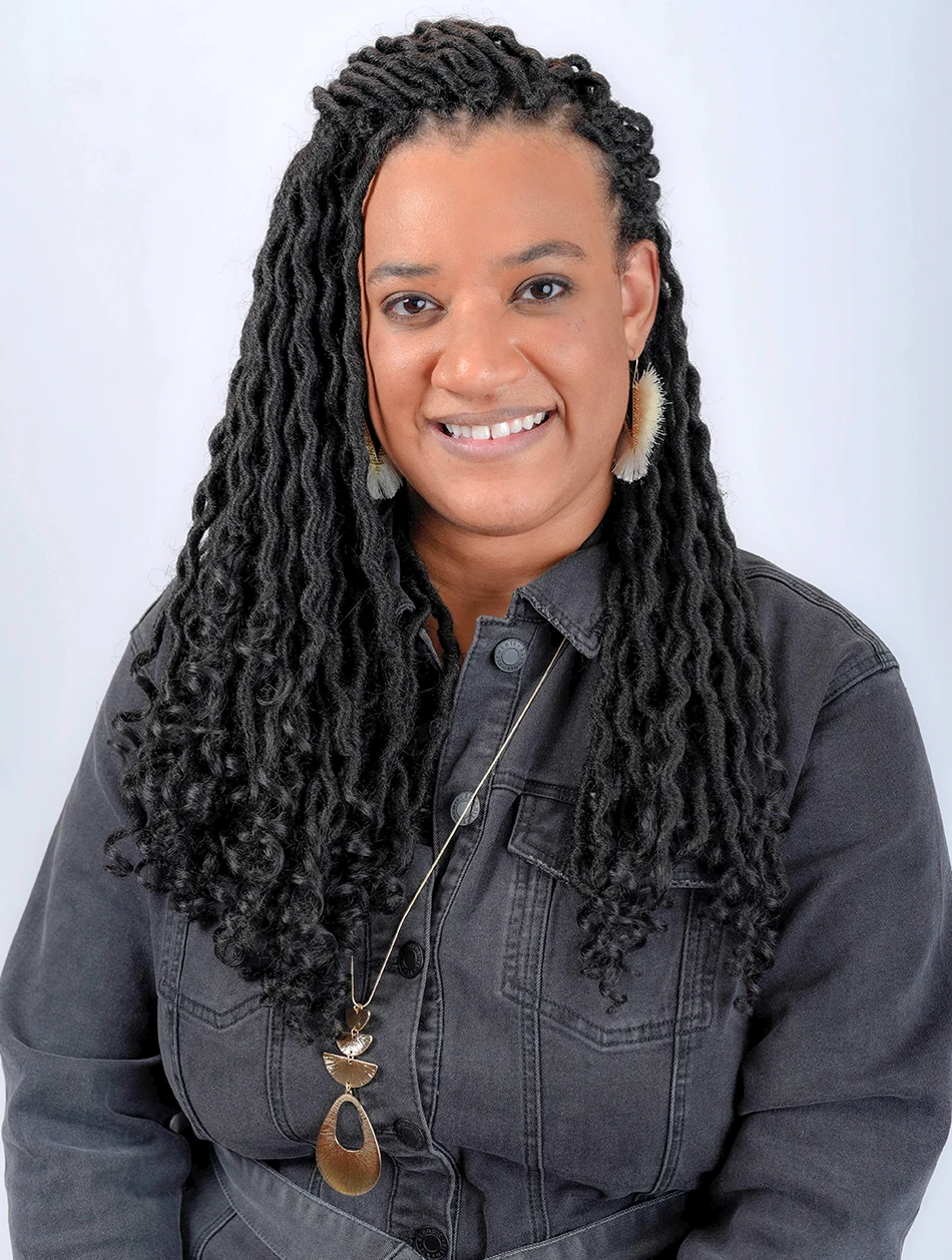 Portrait of Ebony Johnson, smiling, in a gray denim jacket